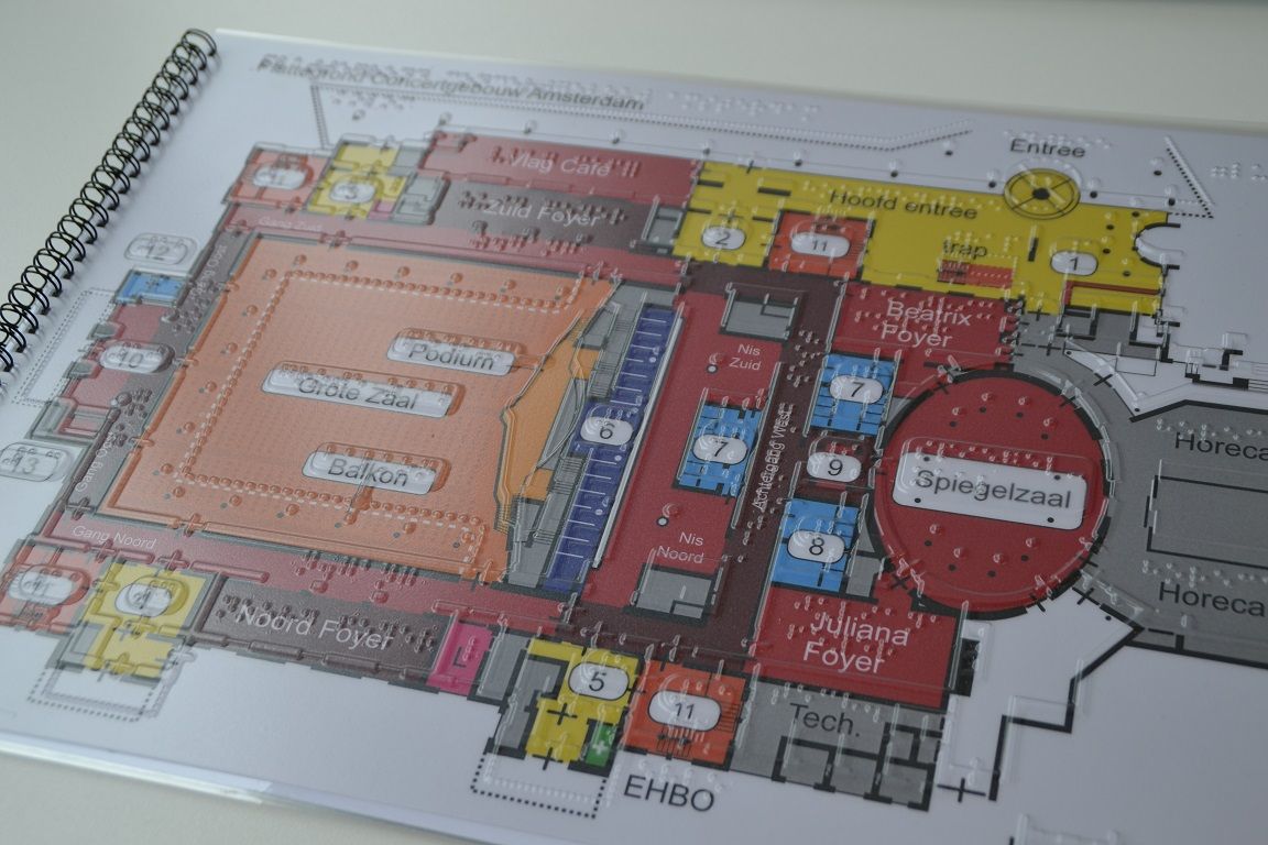 Afbeelding van een plattegrond in kleur met tekst, reliƫf en braille