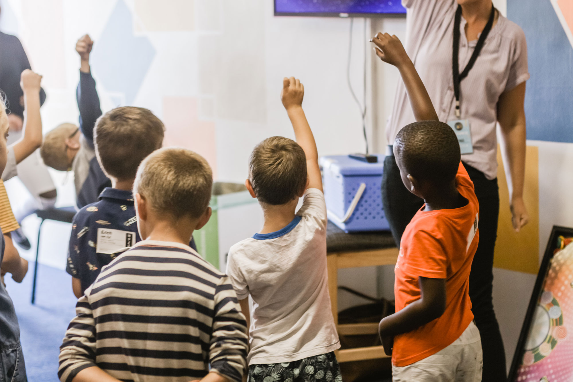 Children in classroom raising their hands